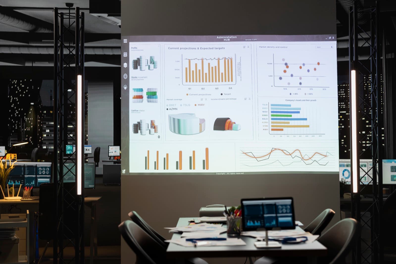 An empty office at night with financial charts on wall displays