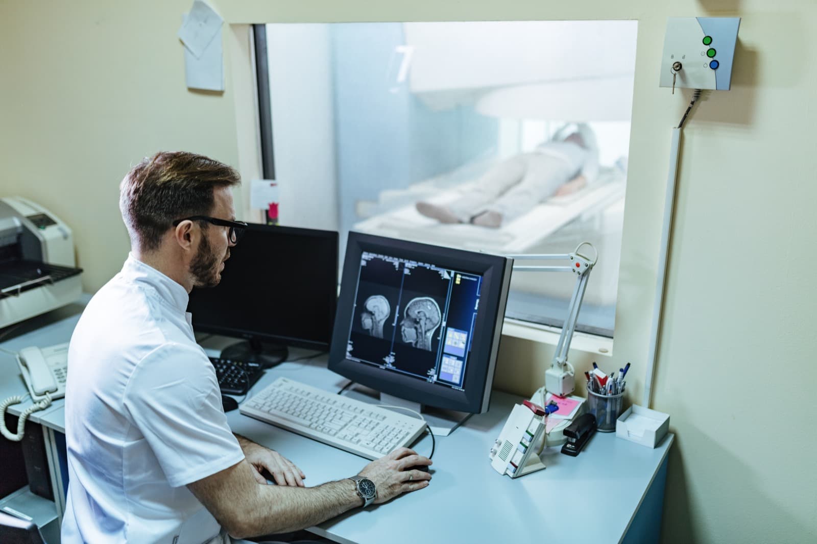A radiologist reviewing scan results on monitors in a control room